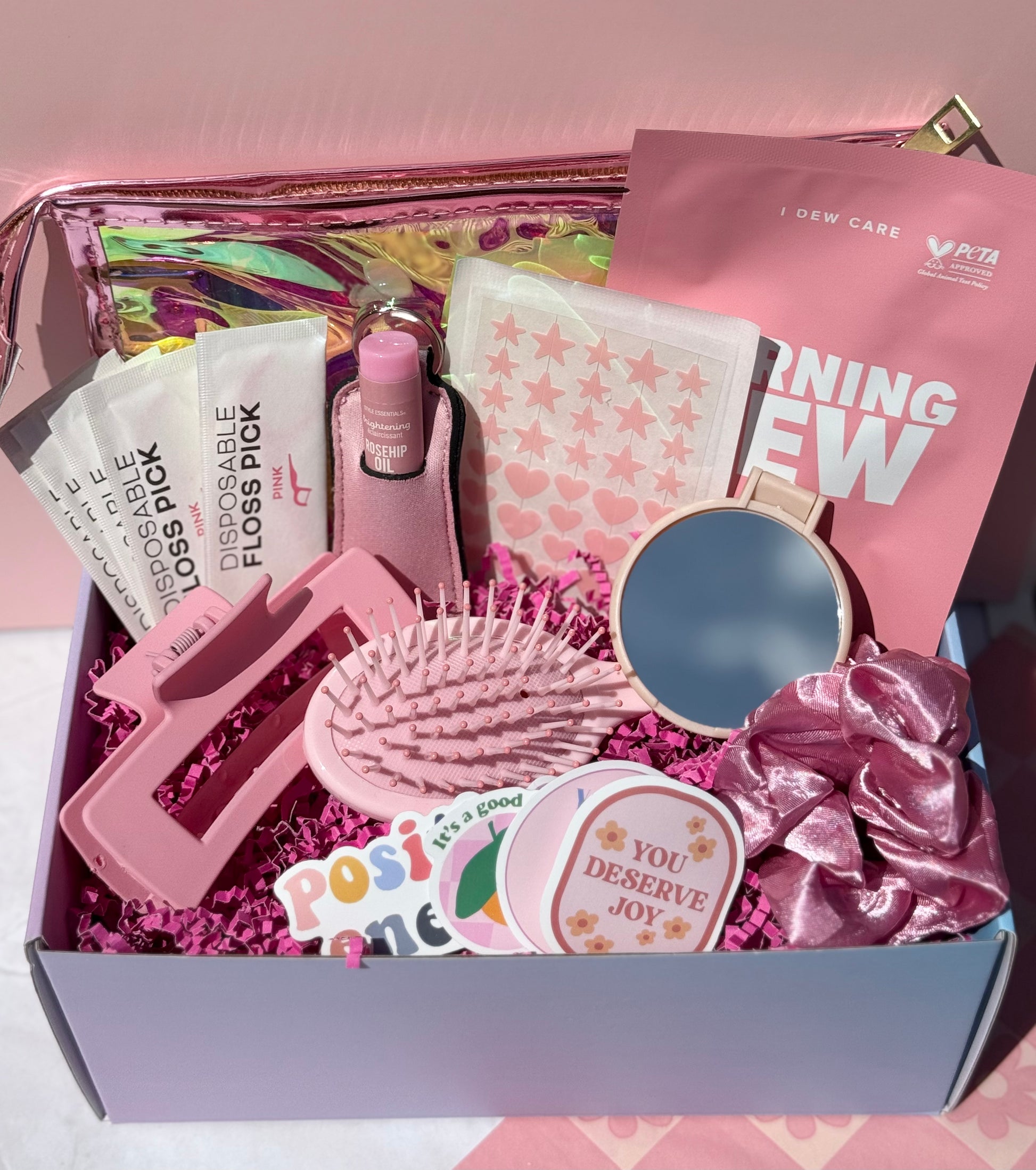 Cute pink self care gift set with fun beauty and glam accessories including claw clip, compact mirror, lip balm and scrunchie